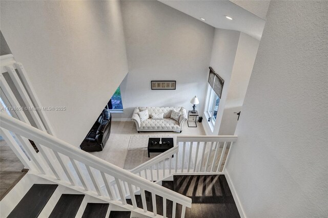 stairway featuring a high ceiling and hardwood / wood-style flooring