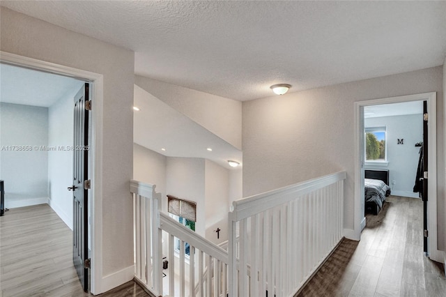 hall with light hardwood / wood-style flooring and a textured ceiling