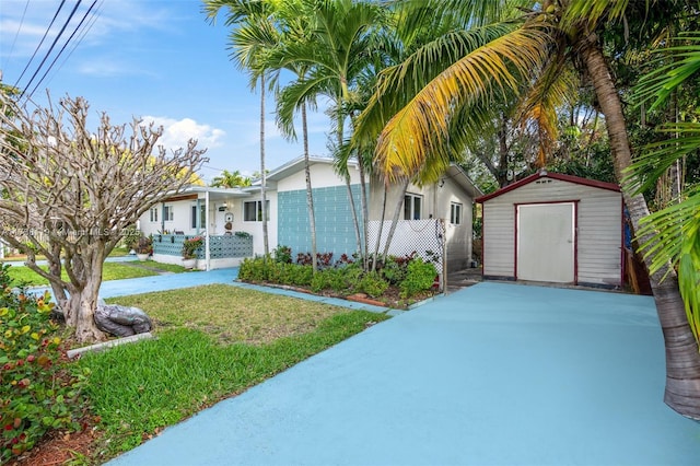 view of front of home featuring a storage shed and a front lawn