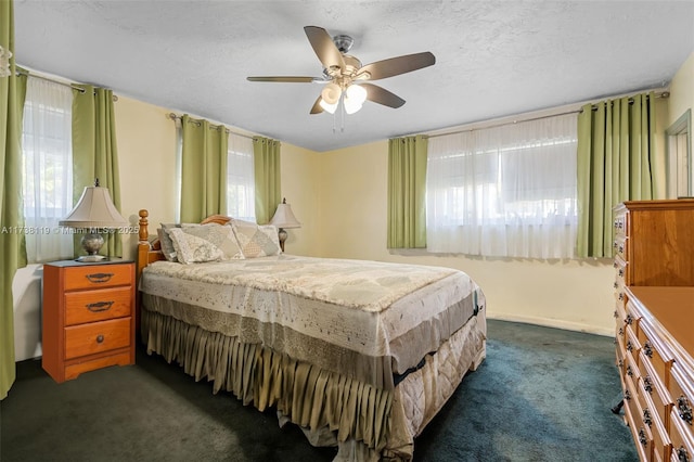 bedroom featuring ceiling fan, dark carpet, and a textured ceiling