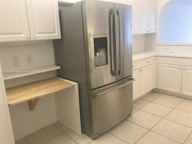 kitchen featuring white cabinetry, sink, light tile patterned flooring, and stainless steel refrigerator with ice dispenser