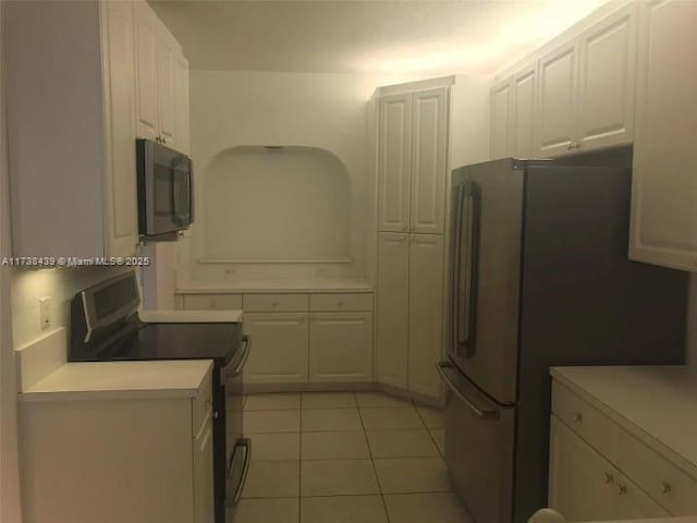 kitchen with light tile patterned flooring, appliances with stainless steel finishes, and white cabinets