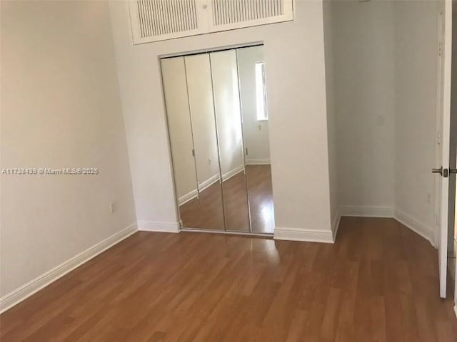 unfurnished bedroom featuring dark wood-type flooring and a closet