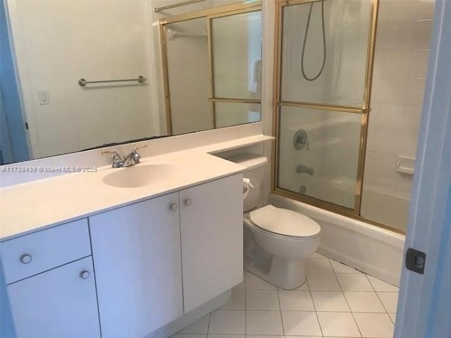 full bathroom with tile patterned flooring, vanity, bath / shower combo with glass door, and toilet