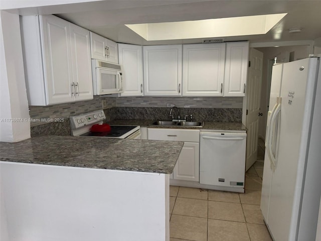 kitchen featuring sink, light tile patterned floors, kitchen peninsula, white appliances, and white cabinets