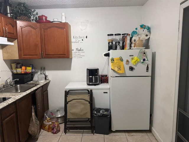 kitchen featuring sink, a textured ceiling, light tile patterned floors, white fridge, and exhaust hood