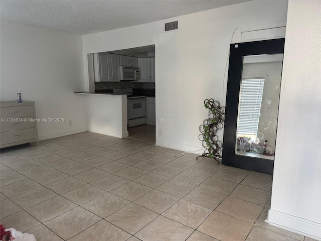 empty room with light tile patterned floors and a textured ceiling