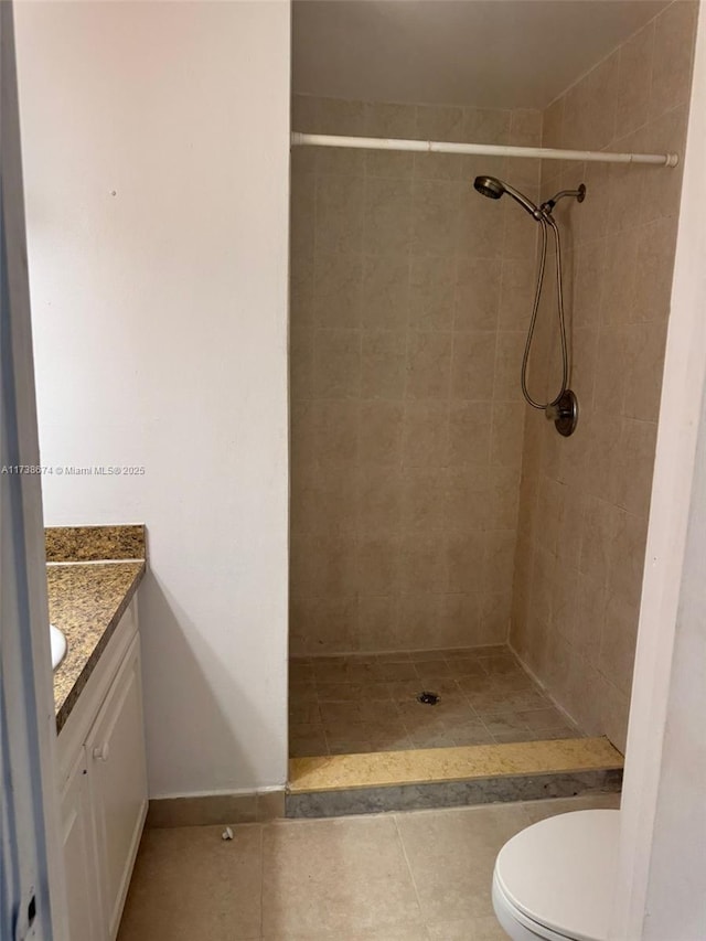 bathroom with vanity, tiled shower, tile patterned floors, and toilet