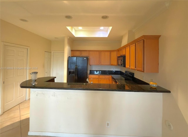 kitchen with dark countertops, a peninsula, a tray ceiling, black appliances, and light tile patterned flooring