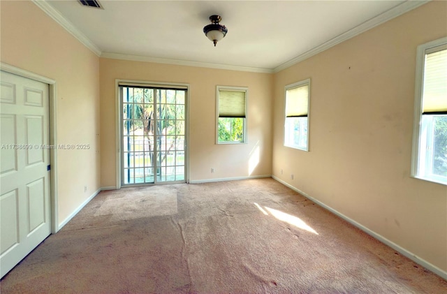 carpeted spare room featuring baseboards, visible vents, and crown molding