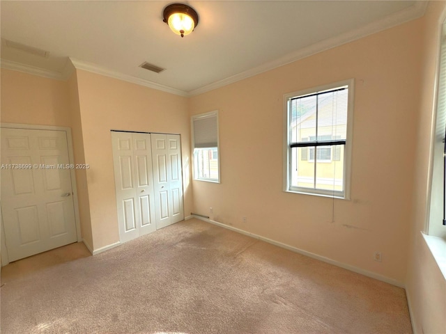 unfurnished bedroom featuring carpet floors, crown molding, a closet, visible vents, and baseboards