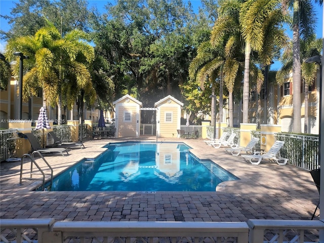 community pool featuring an outbuilding, a patio area, and fence