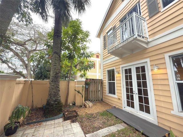 view of yard featuring french doors, a fenced backyard, and a balcony