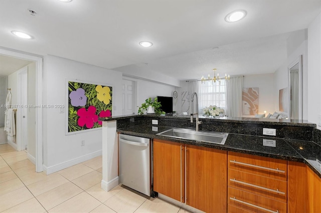 kitchen featuring sink, dark stone counters, stainless steel dishwasher, light tile patterned floors, and an inviting chandelier