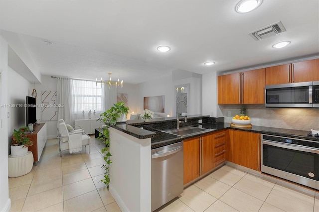 kitchen with sink, dark stone counters, kitchen peninsula, and appliances with stainless steel finishes