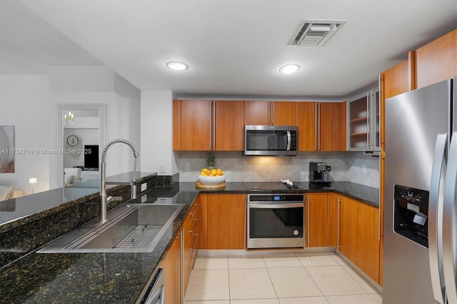 kitchen featuring light tile patterned flooring, stainless steel appliances, sink, and dark stone countertops