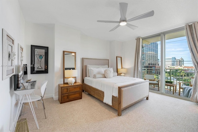 bedroom with access to outside, light colored carpet, expansive windows, and ceiling fan