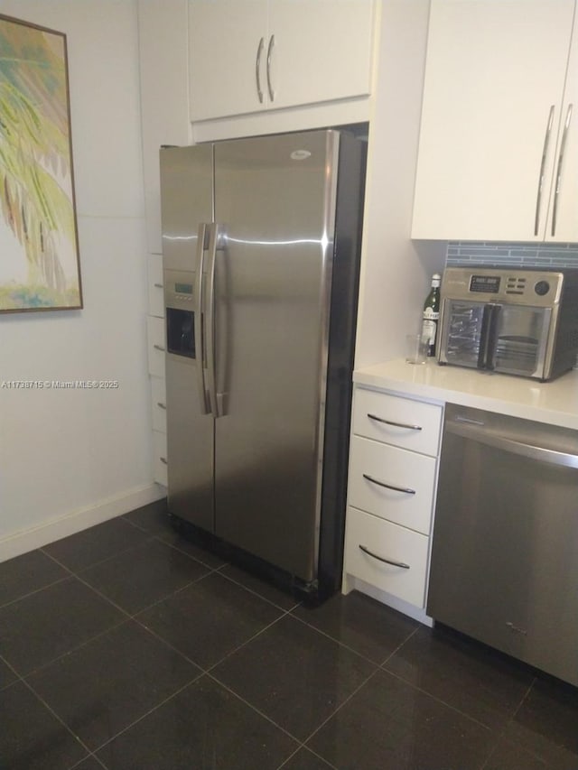 kitchen featuring dark tile patterned floors, white cabinetry, and appliances with stainless steel finishes