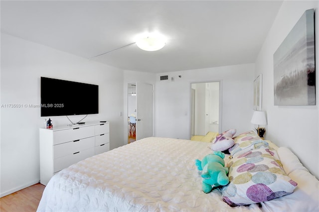 bedroom with ensuite bath and light hardwood / wood-style flooring