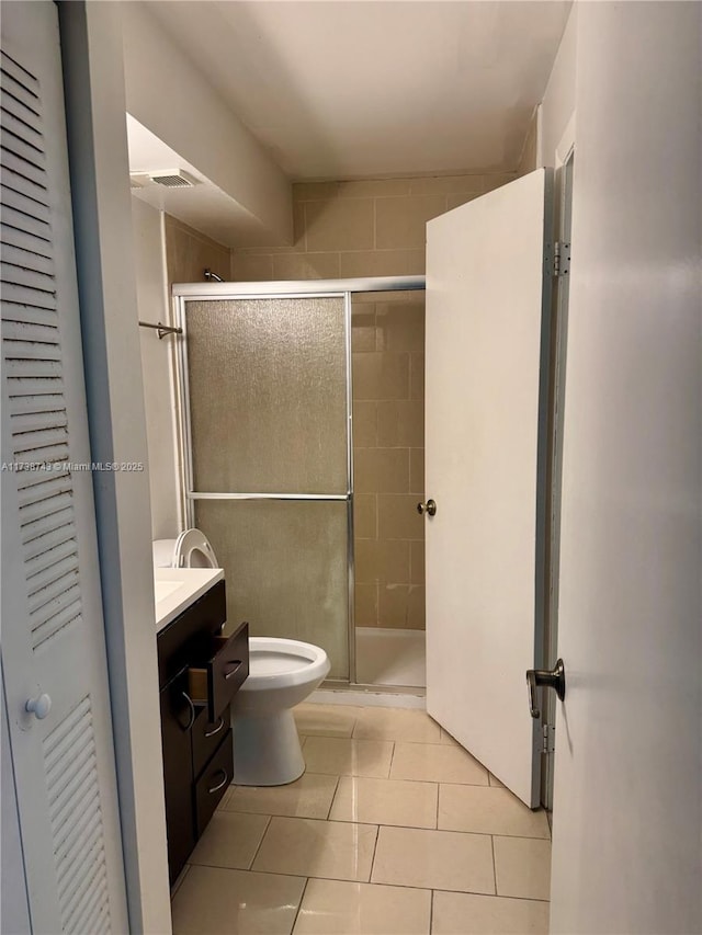 bathroom featuring vanity, toilet, tile patterned flooring, and a shower with door