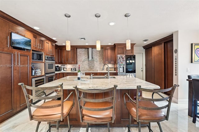 kitchen with appliances with stainless steel finishes, sink, hanging light fixtures, and a large island with sink