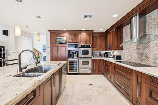 kitchen featuring wall chimney range hood, sink, hanging light fixtures, stainless steel appliances, and light stone counters