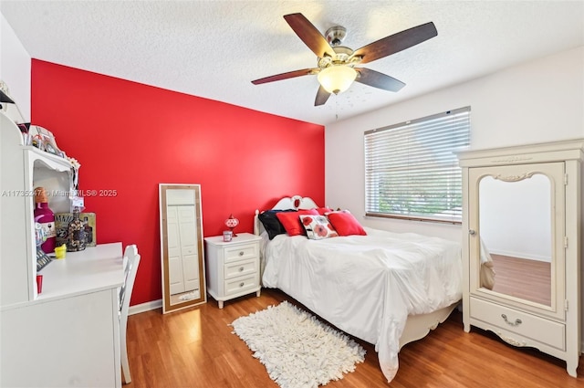 bedroom featuring ceiling fan, hardwood / wood-style floors, and a textured ceiling