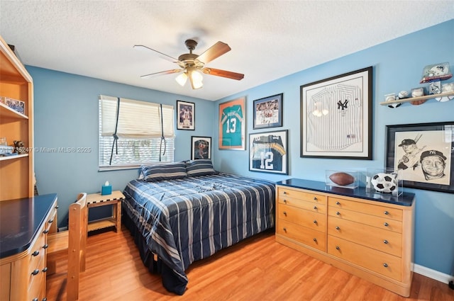 bedroom featuring ceiling fan, hardwood / wood-style flooring, and a textured ceiling