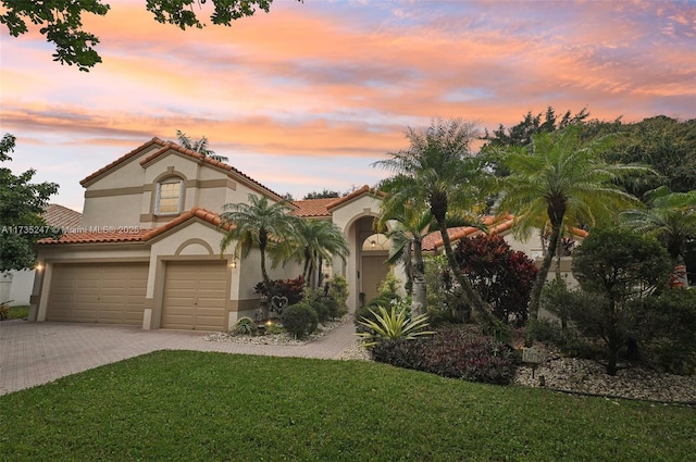 mediterranean / spanish-style house featuring a garage and a yard