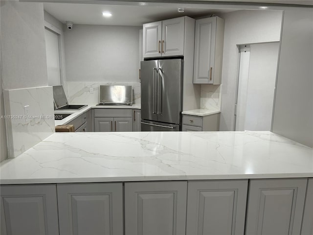 kitchen with gray cabinetry, light stone counters, and high quality fridge