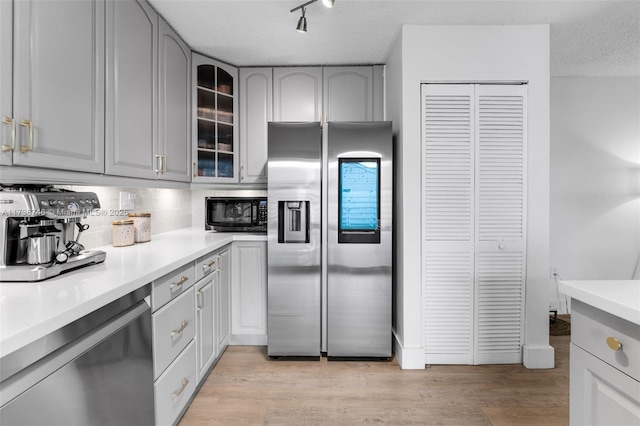 kitchen with gray cabinetry, light hardwood / wood-style flooring, stainless steel appliances, and a textured ceiling