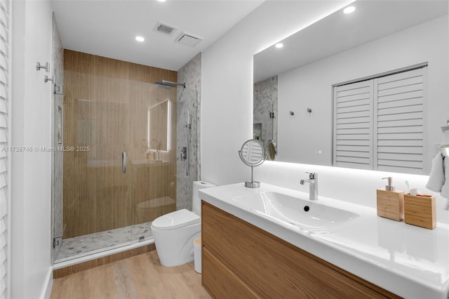 bathroom featuring vanity, hardwood / wood-style floors, a shower with door, and toilet