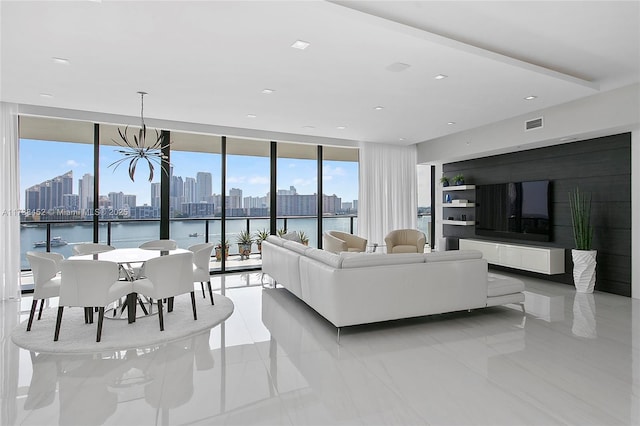 living room with visible vents, a water view, an inviting chandelier, a wall of windows, and recessed lighting