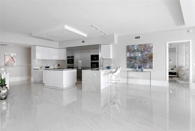 kitchen with white cabinetry, a center island, backsplash, and a kitchen bar