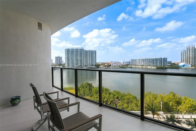 balcony with a water view, visible vents, and a city view