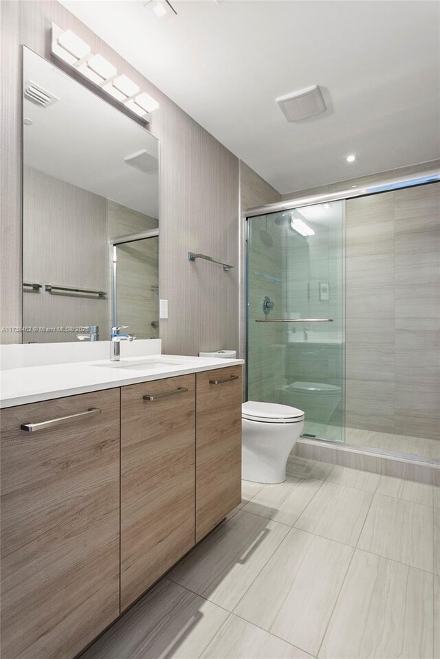 bathroom featuring vanity, a shower with door, and toilet