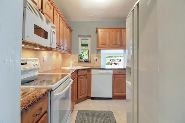 kitchen featuring sink, light tile patterned floors, backsplash, and white appliances