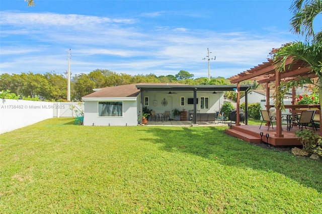 back of property featuring a wooden deck, a pergola, and a lawn