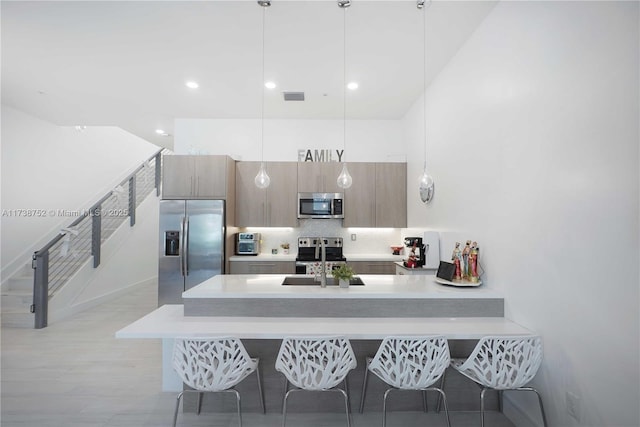 kitchen with hanging light fixtures, tasteful backsplash, appliances with stainless steel finishes, and sink