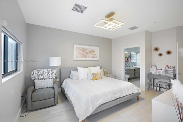 bedroom featuring connected bathroom and light wood-type flooring