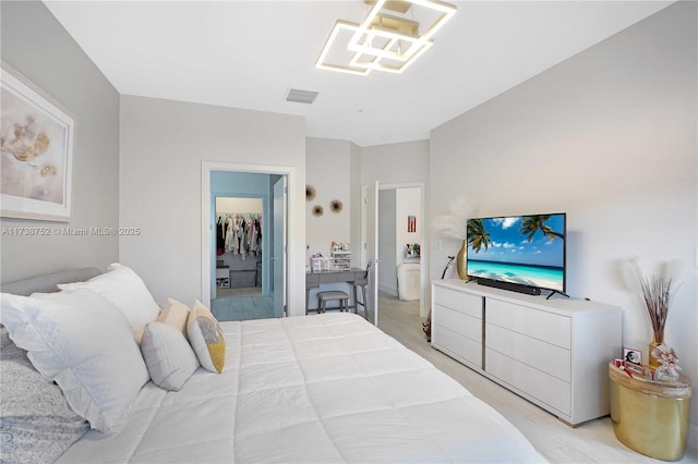 bedroom featuring a walk in closet and light hardwood / wood-style floors