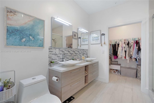 bathroom featuring walk in shower, toilet, vanity, and decorative backsplash