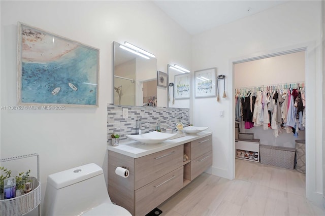 bathroom featuring tasteful backsplash, vanity, toilet, and a shower