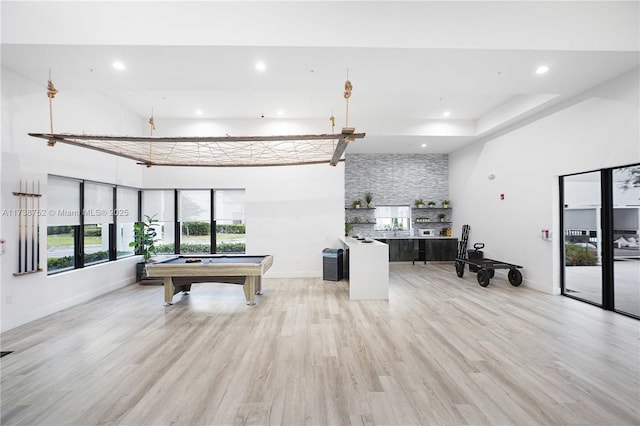 game room featuring a towering ceiling, pool table, and light hardwood / wood-style flooring