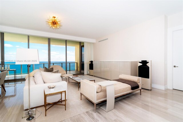 living room with a water view, floor to ceiling windows, and light wood-type flooring