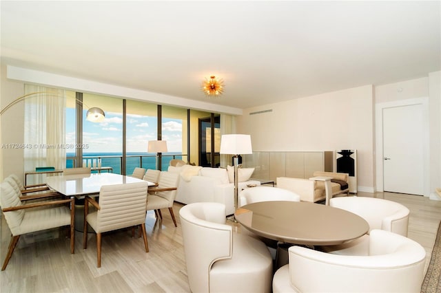 dining room with a water view and light hardwood / wood-style flooring