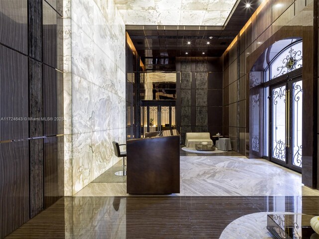 foyer entrance with a towering ceiling and tile walls