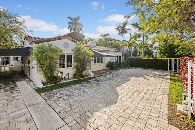 back of property featuring stucco siding, decorative driveway, and fence