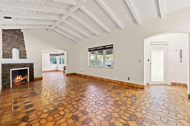 unfurnished living room featuring beam ceiling, arched walkways, and a stone fireplace