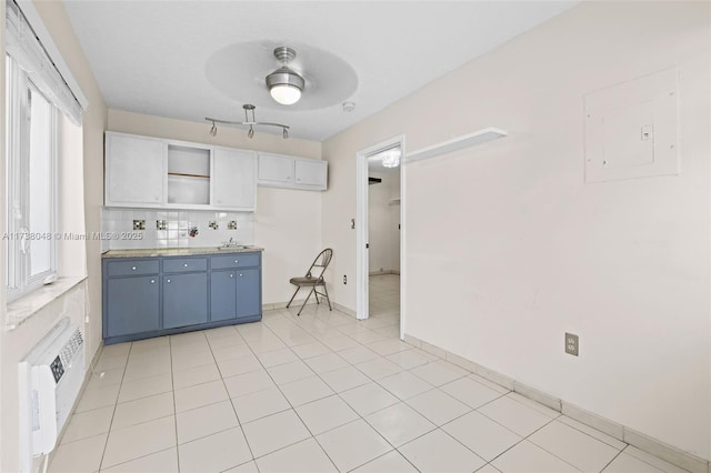 kitchen featuring sink, light tile patterned floors, a wall unit AC, electric panel, and decorative backsplash